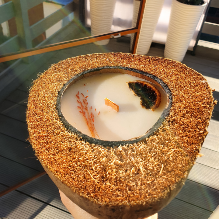 Handgemachte Sojawachs-Kerze in Kokosnussschale mit grünem Tee-Duft, Jasminblüten und getrockneten Früchten, vegan und nachhaltig.