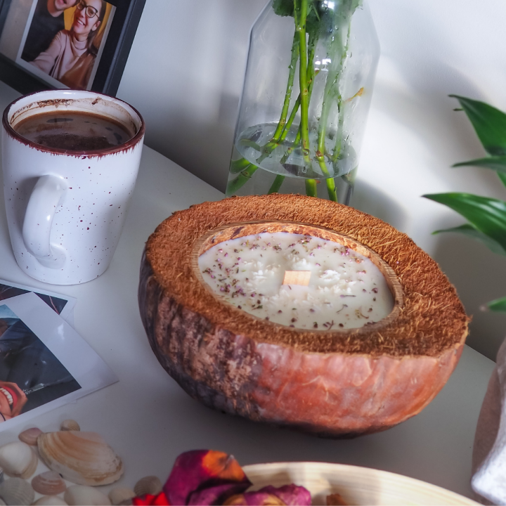 Handgemachte Sojawachs-Kerze in Kokosnussschale mit Kokosmilch-Duft, getrockneten Blumen und Kokosraspeln, vegan und nachhaltig.